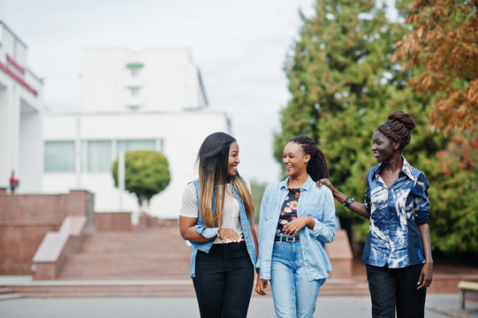 Group of young black female friends hanging out in the city. Multiracial african women walking by the street and discuss.