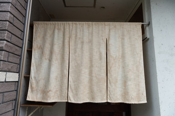 Fototapeta na wymiar The curtain-like fabric that hangs in front of traditional Japanese restaurants and shops not only serves as a signboard, but holds a larger meaning,