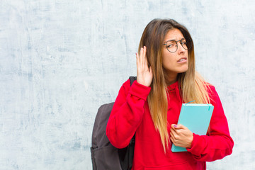 young pretty student looking serious and curious, listening, trying to hear a secret conversation...