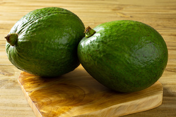 two avocados on wooden base on rustic table