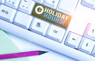 Conceptual hand writing showing Holiday Hours. Concept meaning employee receives twice their normal pay for all hours White pc keyboard with note paper above the white background