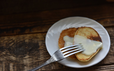 pancakes with condensed milk on a wooden table
