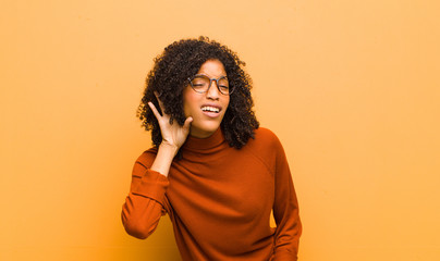young pretty black woman looking serious and curious, listening, trying to hear a secret...
