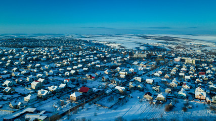 Fototapeta premium aerial view village among the fields and forests in winter. winter landscape snow covered field and trees in countryside.