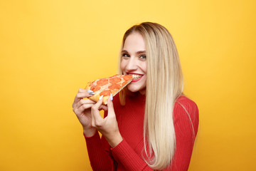 Happy woman eating tasty pizza for lunch in the pink studio