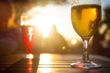 Red wine and cold beer against the sun with male silhouette at background