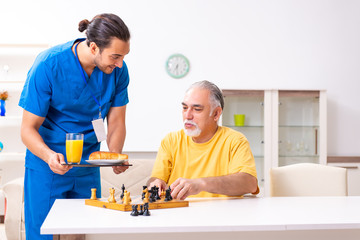 Young male doctor visiting old patient at home