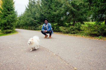african american man walking in street with his fluffy spitz,teaching education dog teams