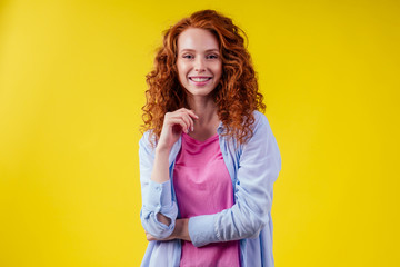 Fototapeta na wymiar redhair ginger curly student woman arms crossed on chest in studio yellow background.foreign language learning concept
