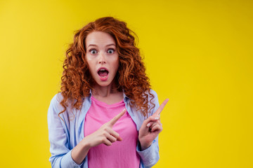 amazed and surprised happy redhead ginger curly woman pointing fingers at copyspace, good emotions...