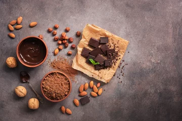 Poster Melted chocolate, cocoa powder, chocolate slices, nuts and mint on a dark rustic background. Top view, flat lay, copy space. © Yulia