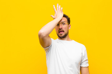 young handsome man raising palm to forehead thinking oops, after making a stupid mistake or...