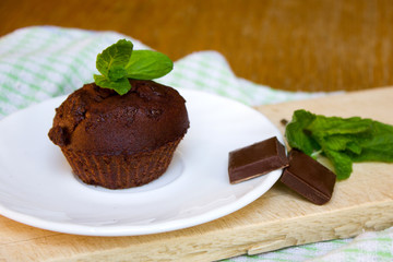 Chocolate Muffin with Mint Leaf on the Saucer in the Kitchen