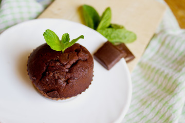 Fototapeta na wymiar Top View of Chocolate Muffin with Mint Leaves on the Saucer in t