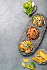 CEVICHE. Three colorful shrimps ceviche with mango, avocado and tomatoes. Latin American Mexican Peruvian Ecuadorian food. Served with white wine and banana chips