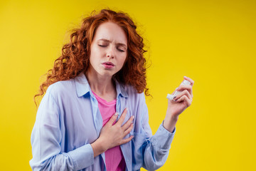 upsad redhead curly ginger tourist student in a blue shirt having asthma using the asthmas inhaler...