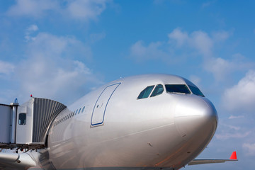 View of the bow of a passenger plane and the cockpit with a wing at the gangway.