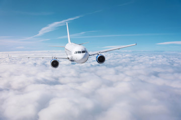 Passenger plane flies over overcast on a sunny day.
