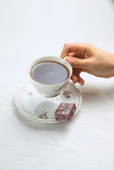 White porcelain tea cup on a white background in womans hands