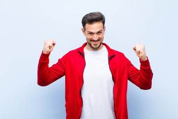 young handsome sports man or monitor feeling happy, positive and successful, celebrating victory,...