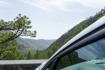 Vehicle parked in front of a green natural park on a view point. Panoramic of field and remote land.