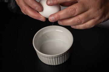An egg about to be cracked into a bowl to make cookies