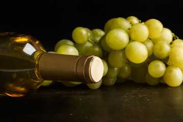 Botella de vino blanco con uvas vista de frente y de cerca