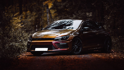 Autumn photo with a tuned car on the road - obrazy, fototapety, plakaty