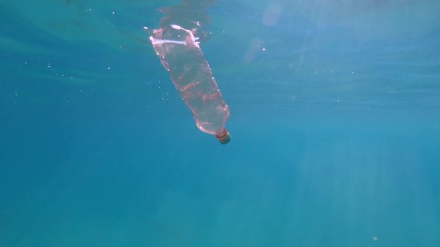 Underwater shoot of a dirty discarded plastic bottle floating in the sea