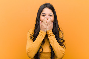 young pretty hispanic woman happy and excited, surprised and amazed covering mouth with hands,...