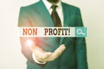 Writing note showing Non Profit. Business concept for not making or conducted primarily to make profit organization Man in front of table. Mobile phone and notes on the table
