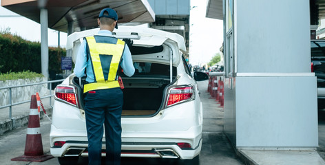 Back view of Thai security guard checking car truck at the entrance to the parking lot at shopping...