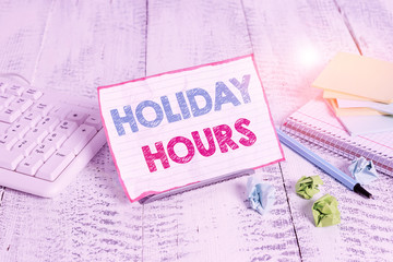 Text sign showing Holiday Hours. Business photo showcasing employee receives twice their normal pay for all hours Notepaper stand on buffer wire in between computer keyboard and math sheets