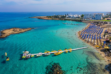 Obraz premium Water activities and pier on the turquoise sea water near the beach. Aerial view from above. Cyprus, Agia Napa