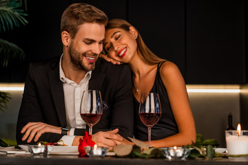 Excited loving couple celebrating special event with wine and candles , having dinner together