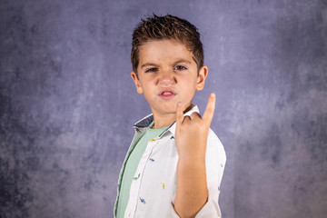 Happy cute child screaming and doing heavy metal rock sign.