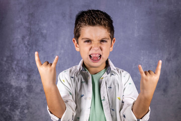 Happy cute child screaming and doing heavy metal rock sign.