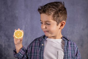 Fototapeta premium Cute child showing a lemon isolated in blue