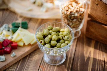 Cheese set on a plate laid out on a beige background. Different types of cheeses: Camembert, Parmesan, blue cheese, olives