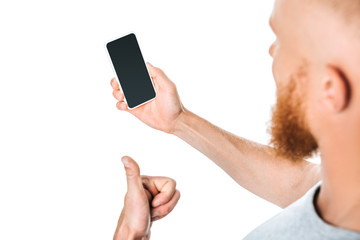 cropped view of man holding smartphone with blank screen and showing thumb up, isolated on white