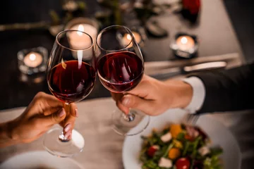 Poster Close up van jong koppel roosteren met glazen rode wijn in restaurant © InsideCreativeHouse
