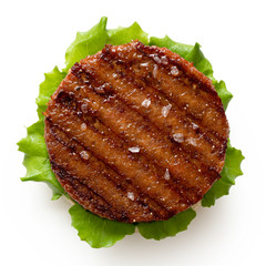 Freshly grilled plant based burger patty on bun with lettuce and rock salt isolated on white. Top...
