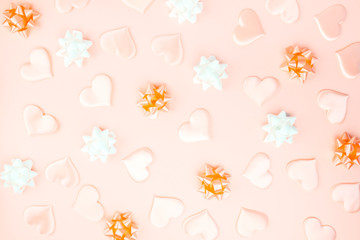 Beautiful silk hearts, white and orange holiday bows on a orange background, pastel colors . Celebrate concept. Flat lay .