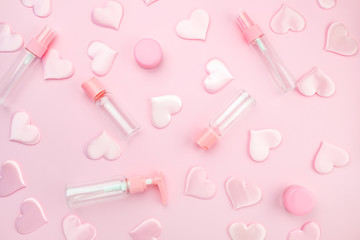 Empty jars for cosmetics and hygiene products, a set for a flight in a pink airplane on a pink background, decorated with pink silk hearts. Beauty concept. Flat lay.