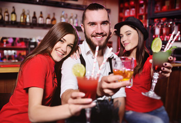 Time Selfie. A group of friends at a party in a nightclub clink glasses with alcoholic beverages. Happy young people with cocktails in the pub.