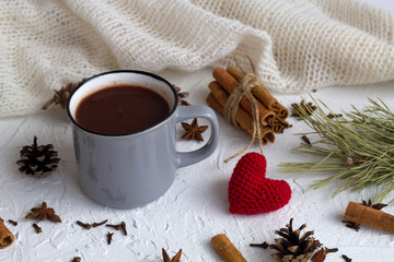 grey cup of hot chocolate and cinnamon, anise star and knitted red heart on white background. horizontal. winter and autumn hot drinks