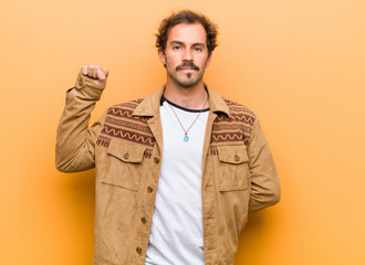 young handsome man feeling serious, strong and rebellious, raising fist up, protesting or fighting...
