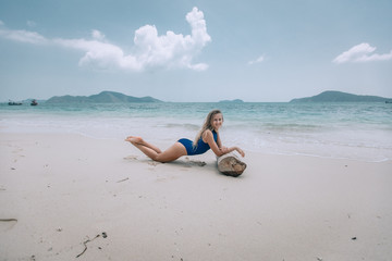 Fototapeta na wymiar Sexy young woman in a great fit lying on a sandy warm beach of Thailand and having a sunbath