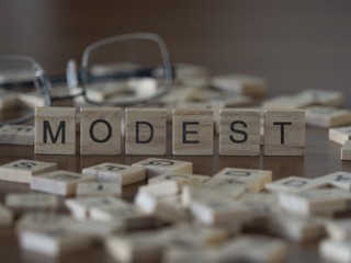 The concept of Modest represented by wooden letter tiles
