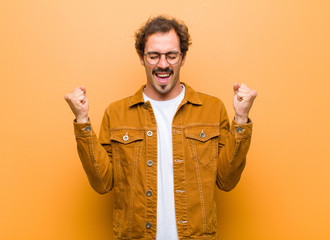 young handsome man looking extremely happy and surprised, celebrating success, shouting and jumping...